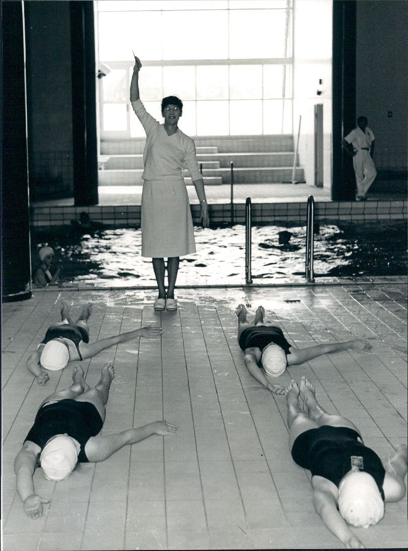 Svømmelærerinde Anne Knudsen instruerer en skoleklasse i svømning. 1964. Foto: Erik Olsen. Frederiksberg Stadsarkiv.